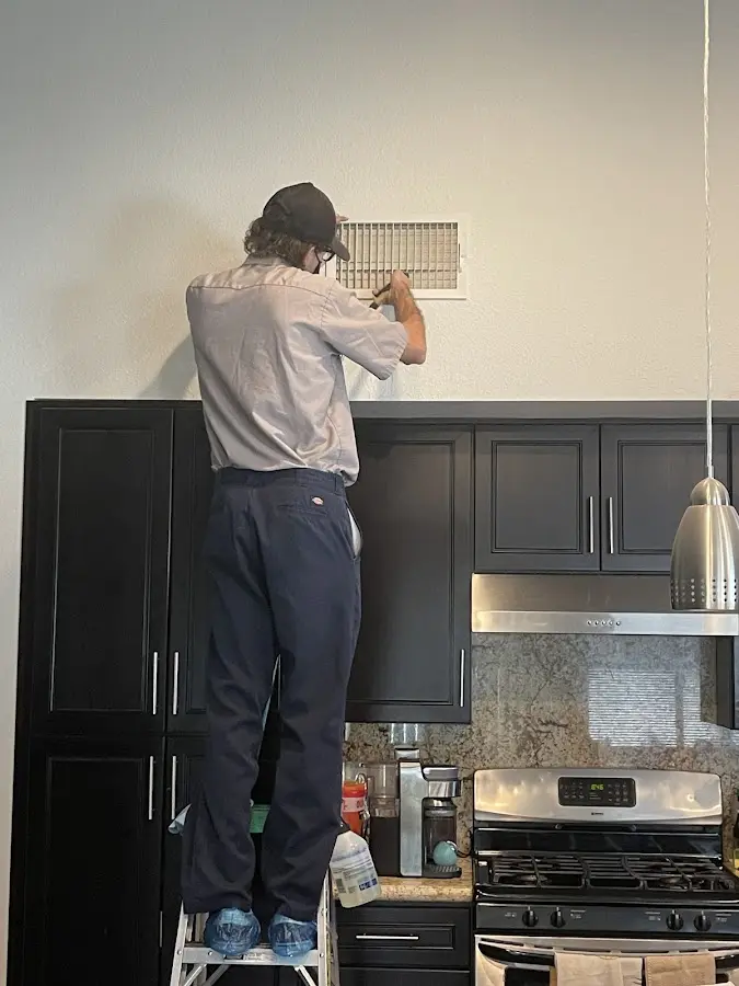 Technician inspecting an air vent during HVAC service in Farmington